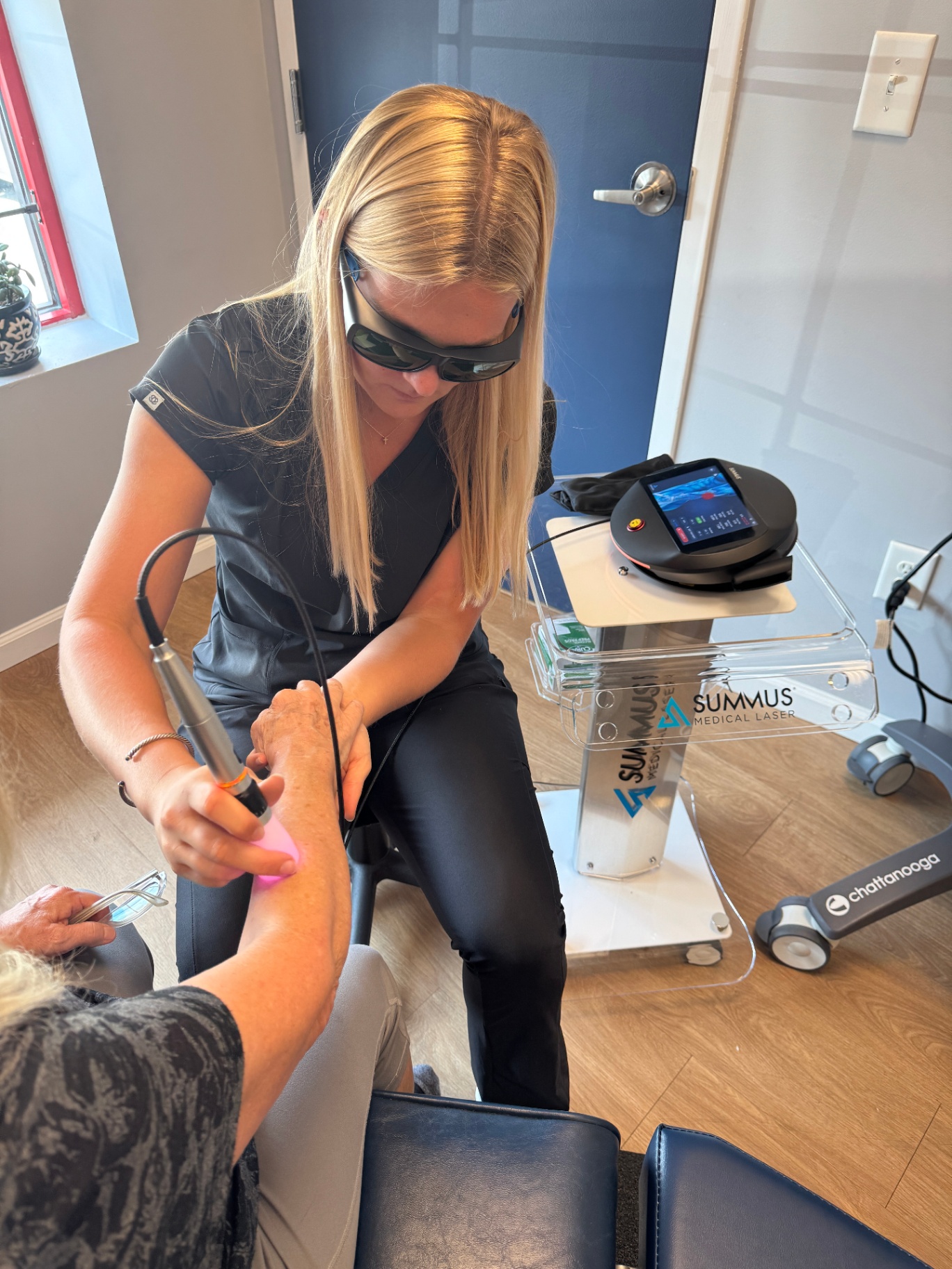 Assistant performing laser therapy on a wrist